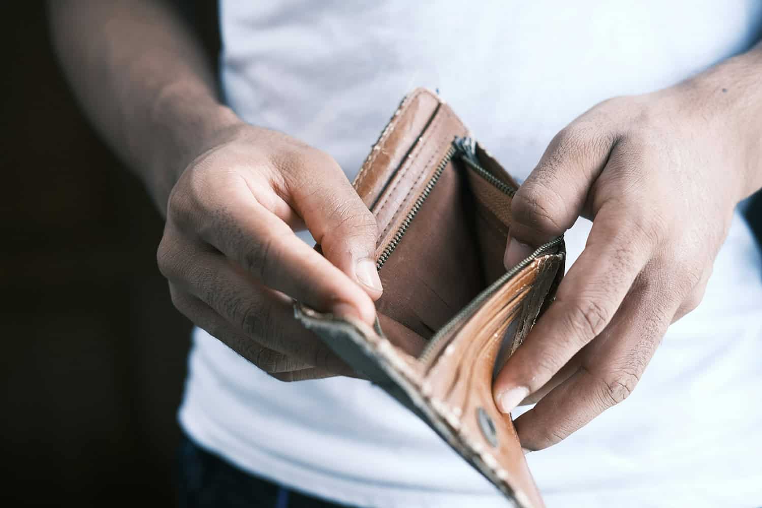 hombre abriendo una cartera vacía de dinero